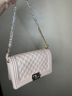Nude quilted handbag with a chain strap held against a plain background