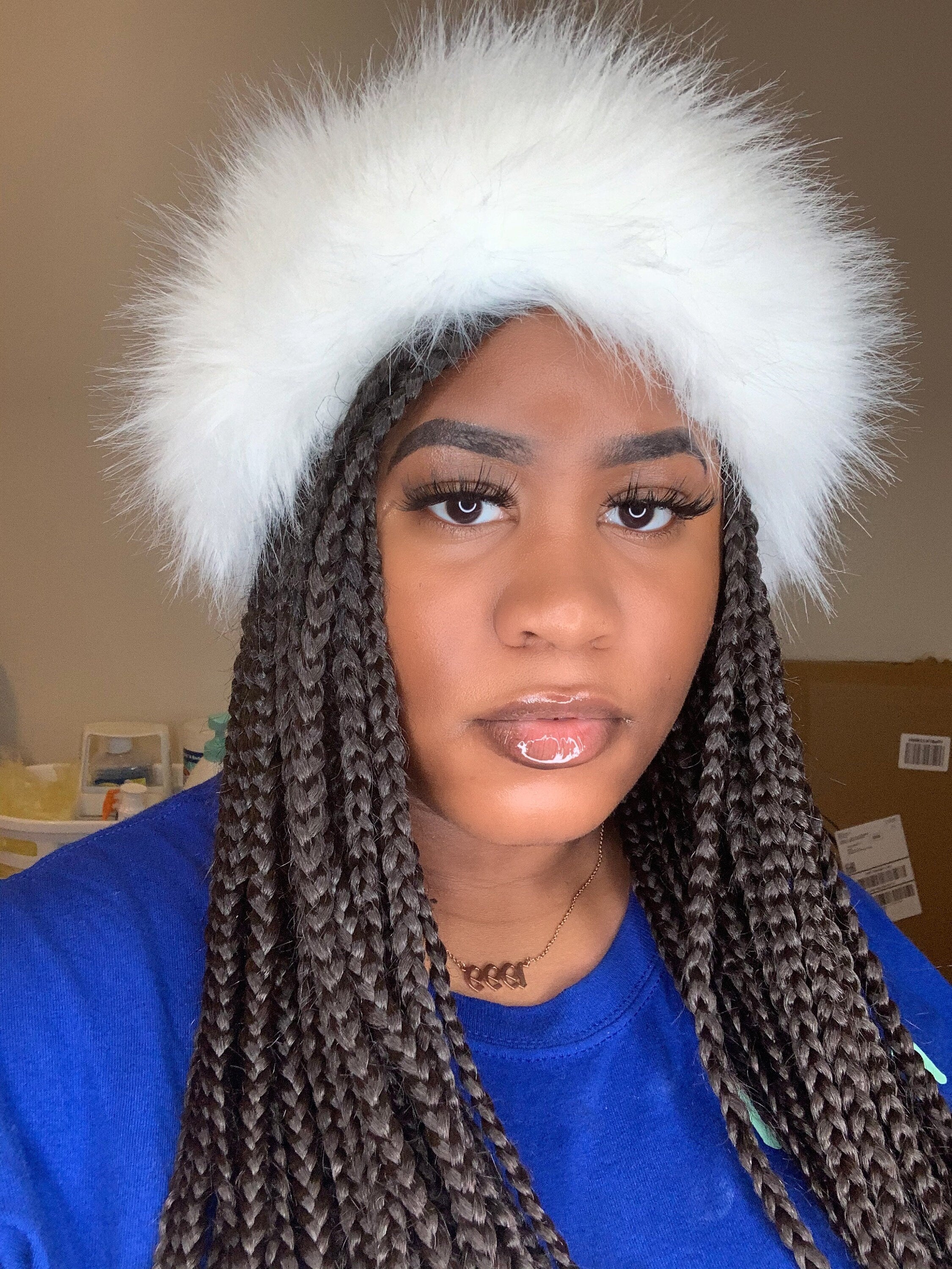 Person wearing a white furry headband with a neutral background