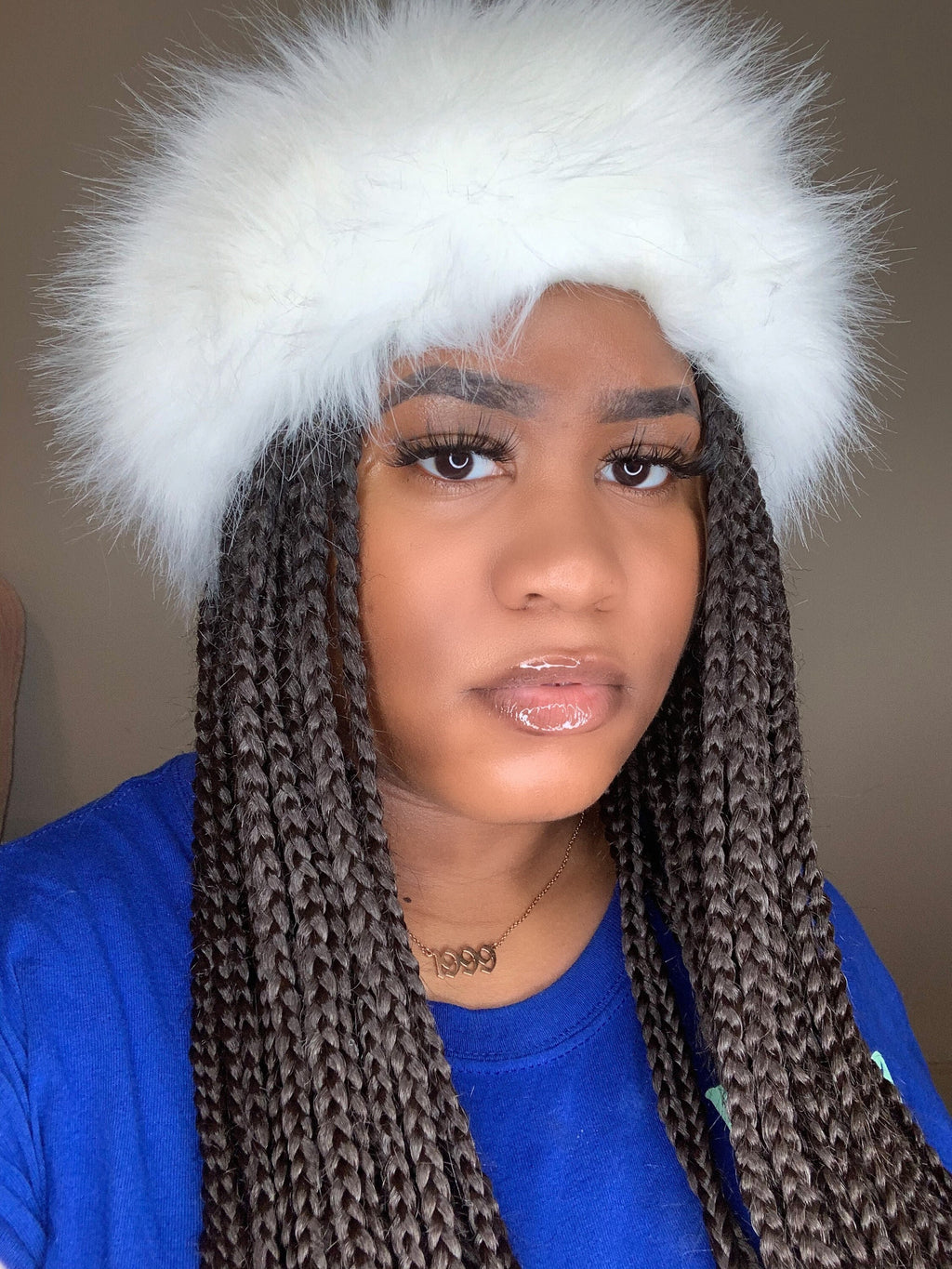 Person wearing a white furry headband with a neutral background