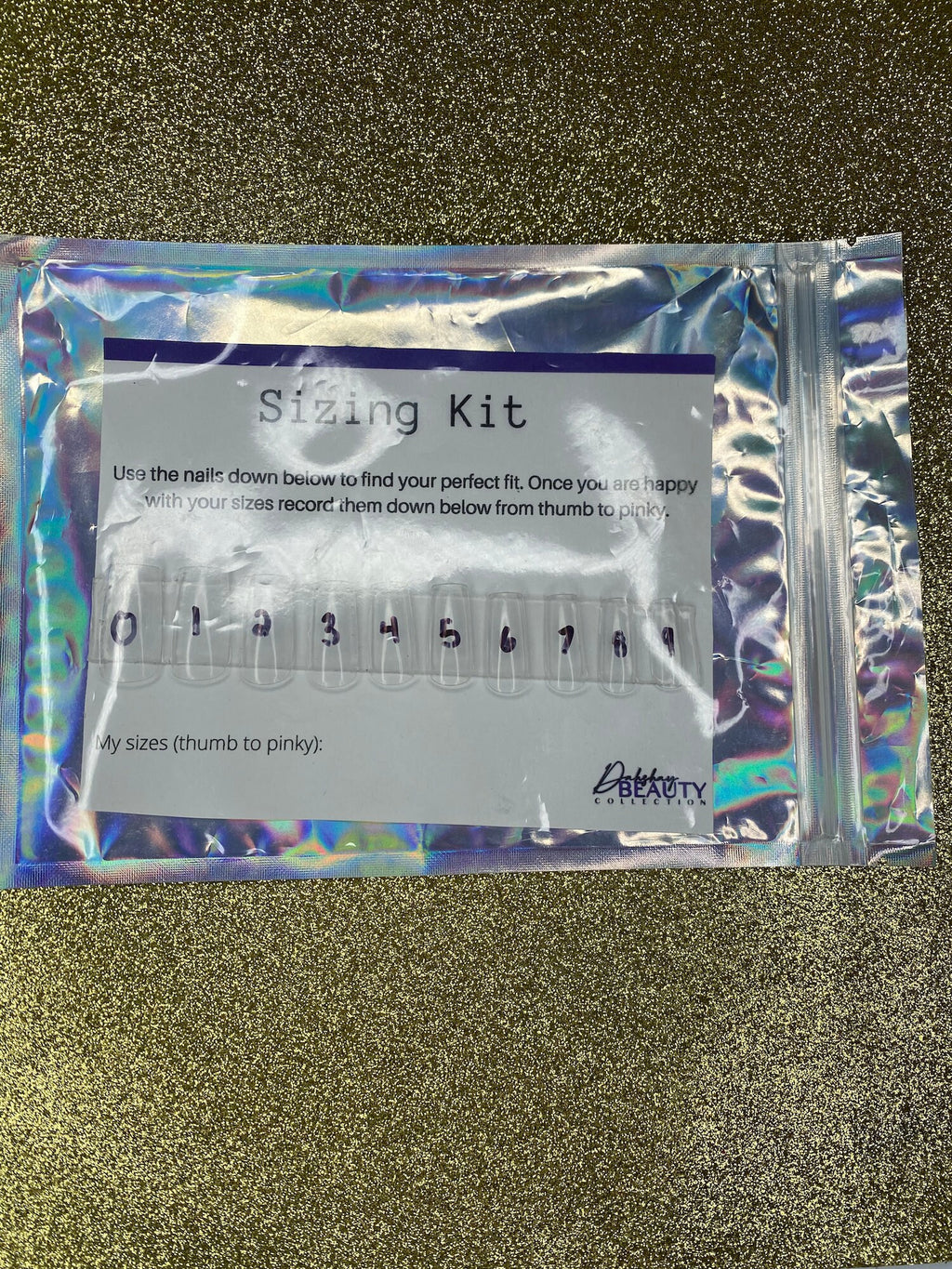 Sizing kit for false nails in a clear plastic package on a glittery black background