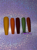 Set of false nails in various Fall colors with a purple glitter background.