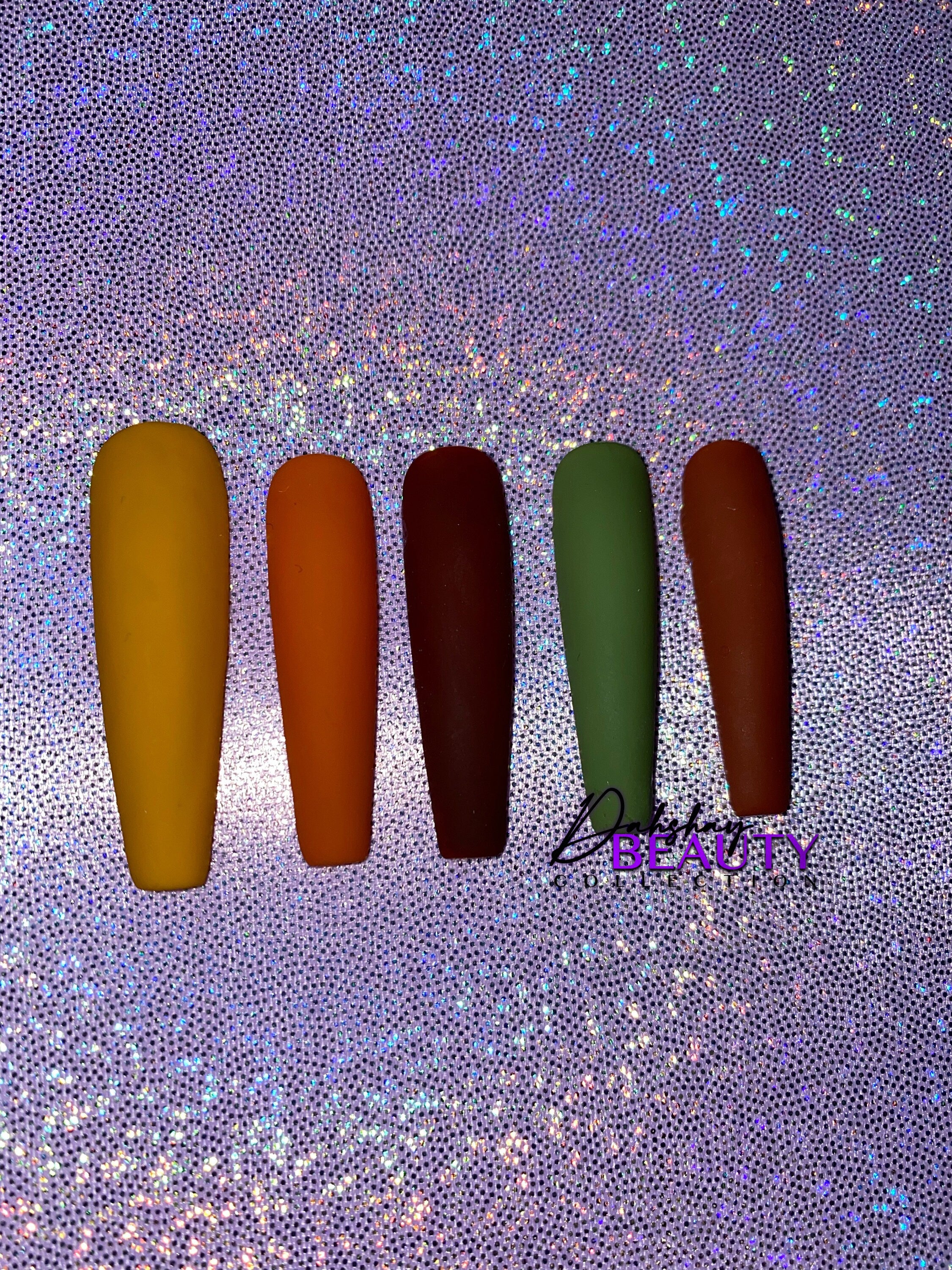 Set of false nails in various Fall colors with a purple glitter background.