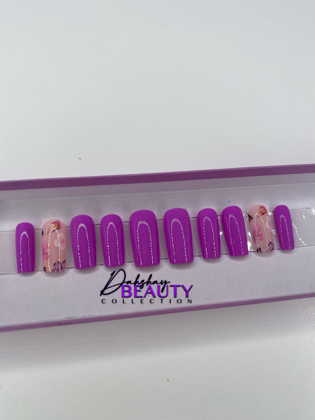 Purple press on nails with a floral design in a display case.