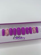 Purple press on nails with a floral design in a display case.