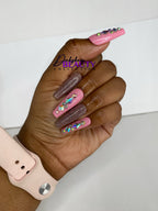 Hand with pink and glitter gradient nails with rhinestones, wearing a beige apple watch.