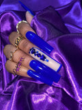 Blue nails with a rhinestone design on a purple satin background