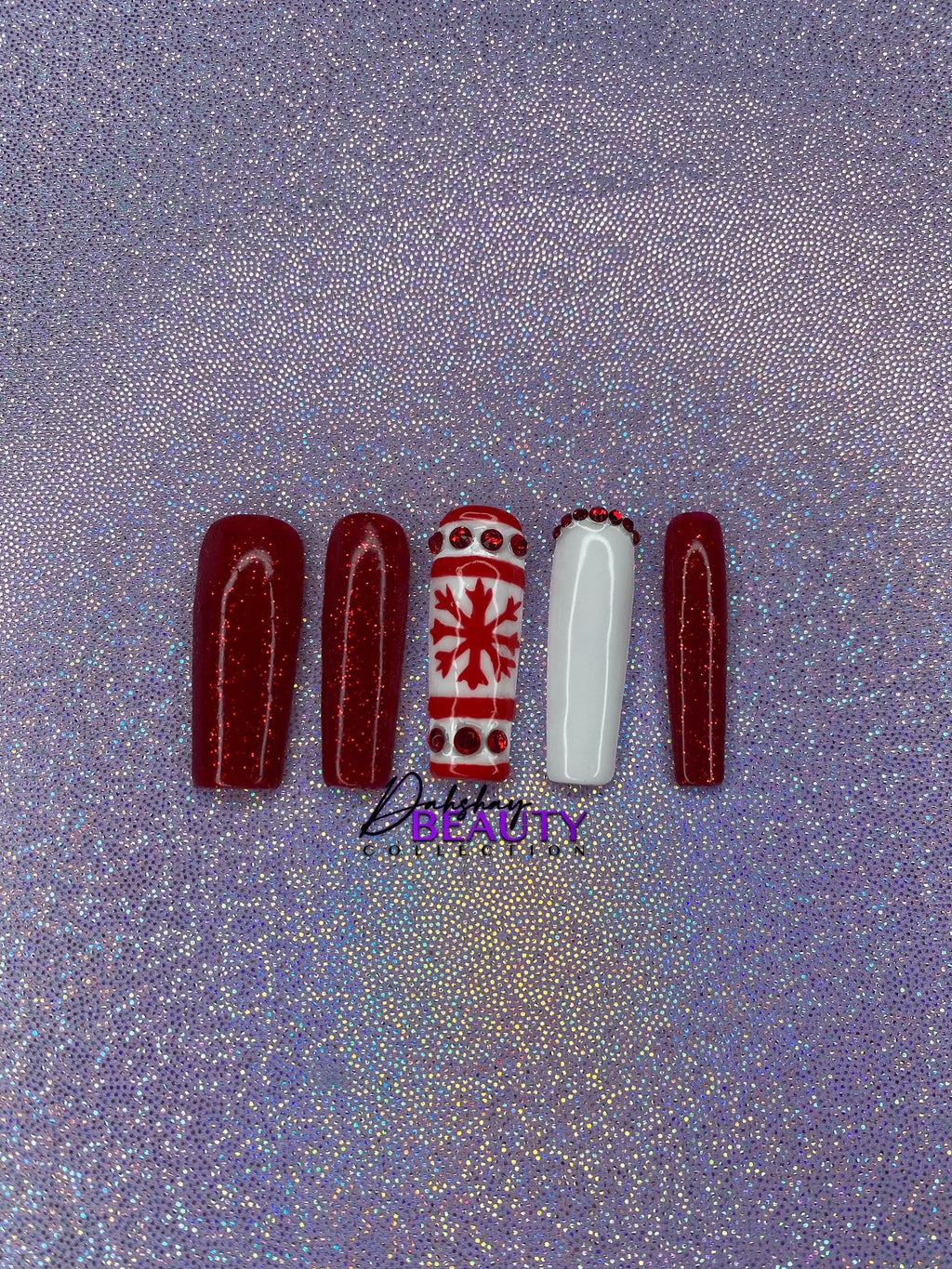 Set of Christmas red and white press on nails with red glitter and a snowflake design on a glittery purple background.