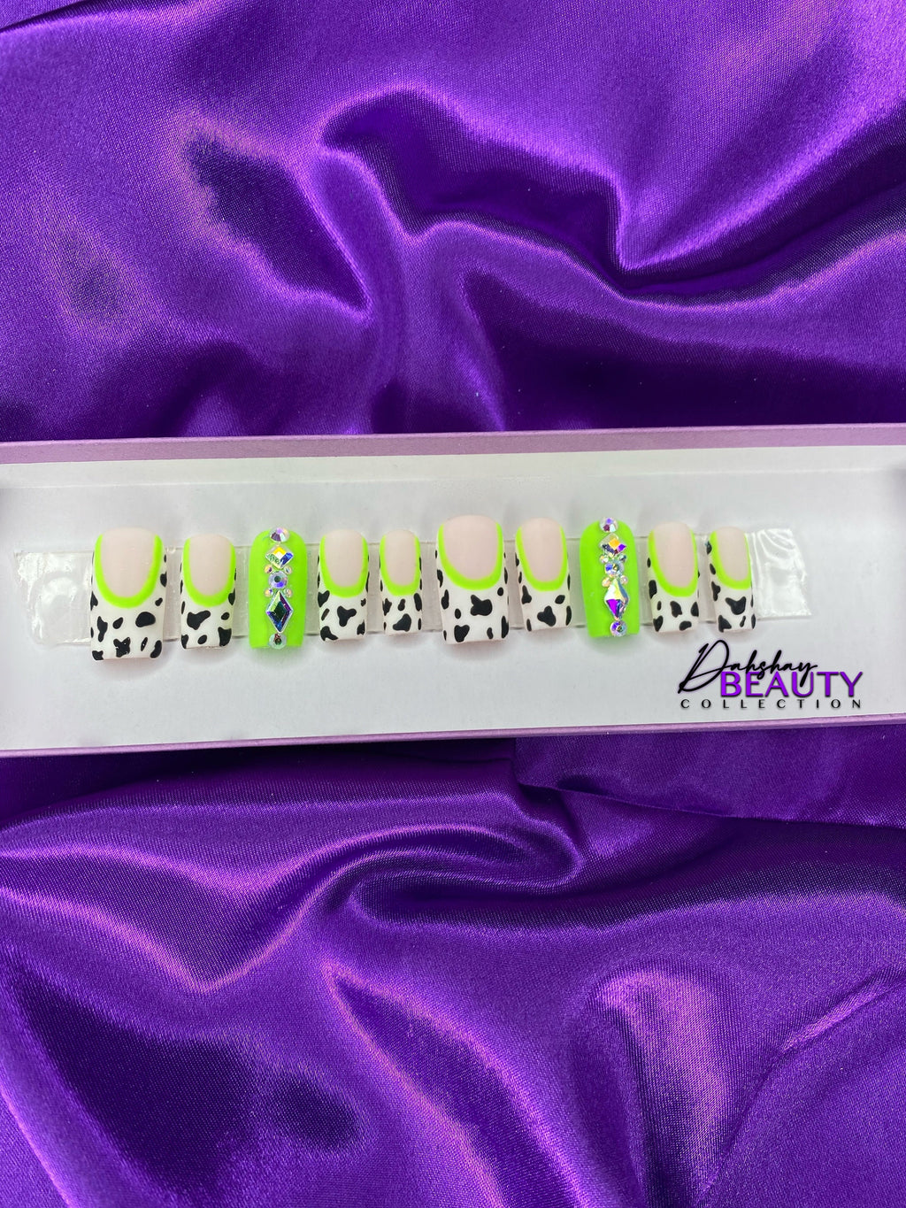 Set of false nails with cow print design on a purple satin background