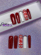 Set of Christmas red and white press on nails with red glitter and a snowflake design on a glittery purple background.