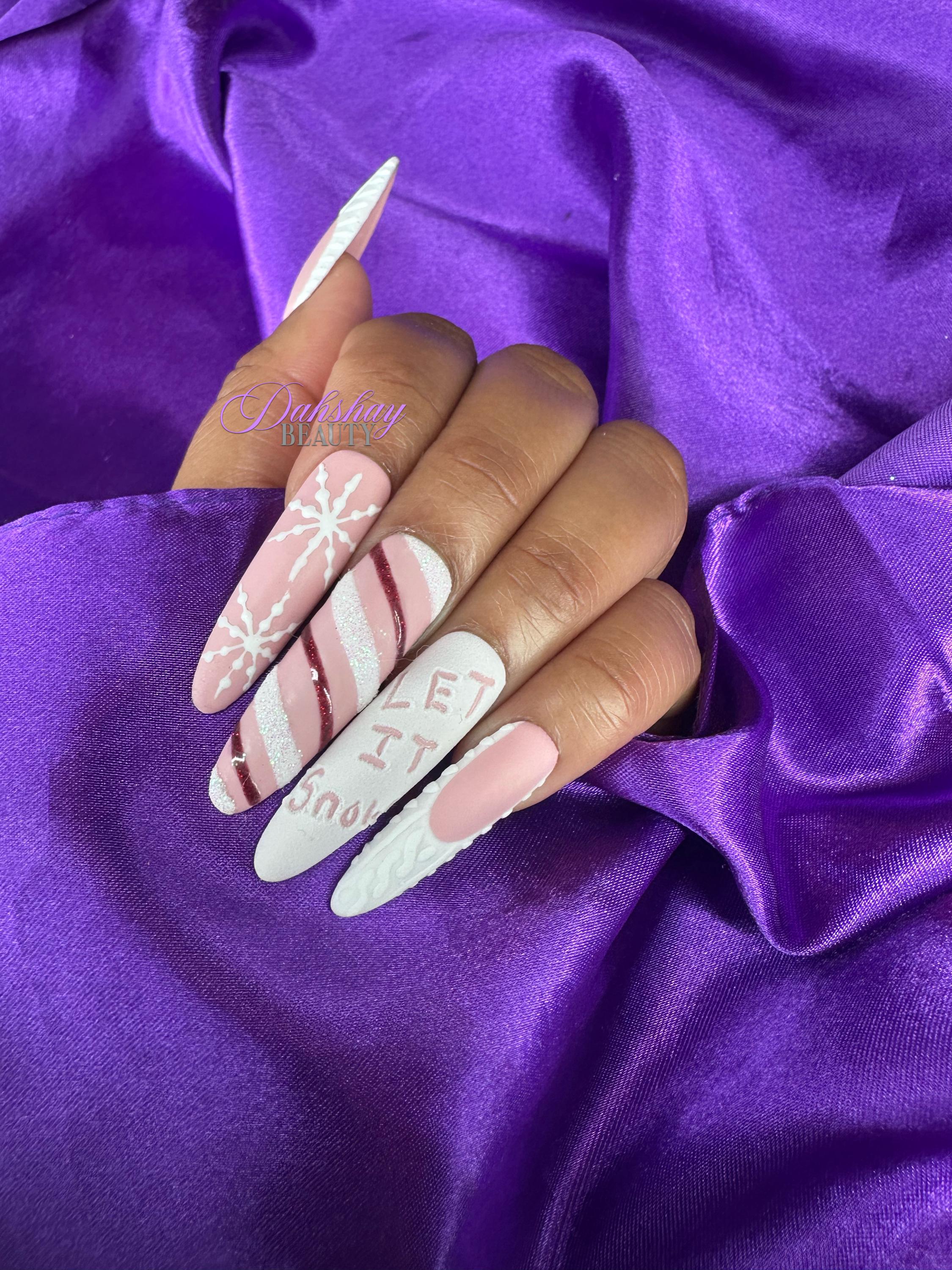 Set of Christmas false nails with snowflake, candy cane and sweater designs on a purple satin background.