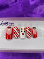 A set of Christmas nails with a reindeer, candy cane and french tip design on a purple satin background.
