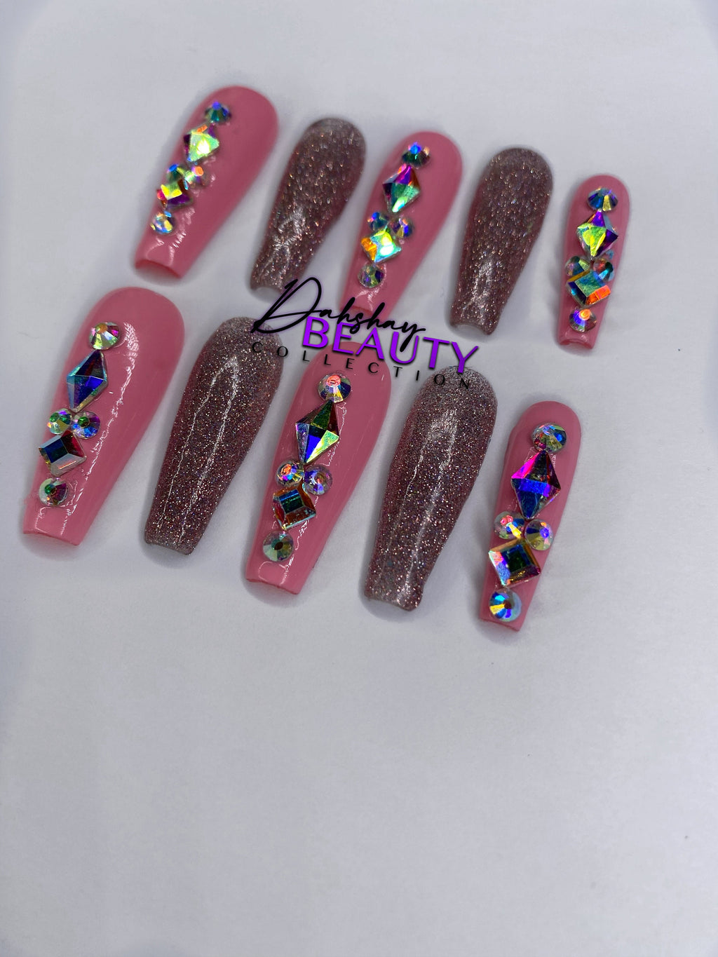 Pink and pink glitter press on nails with rhinestone decorations on a white background.