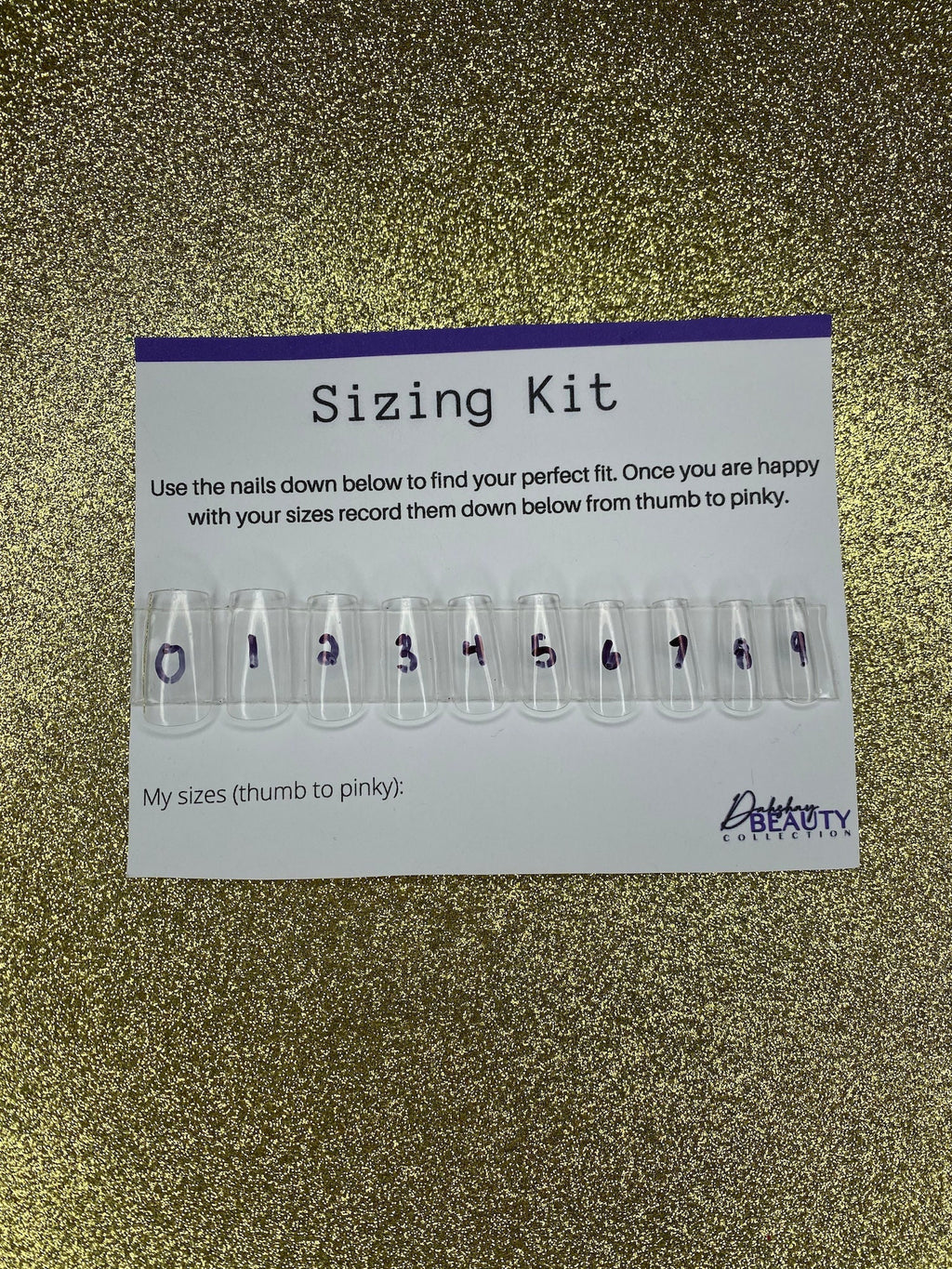 Nail sizing kit with clear nail forms and measurement labels on a gold glitter background.