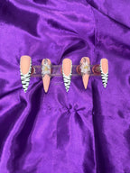 Set of false nails with zebra print design  and a floral design on a purple satin background