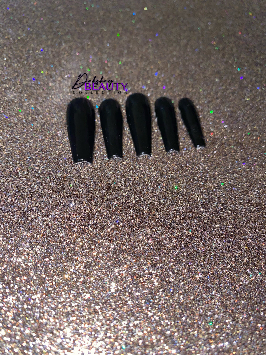 Set of black false nails on a glittery gold background.