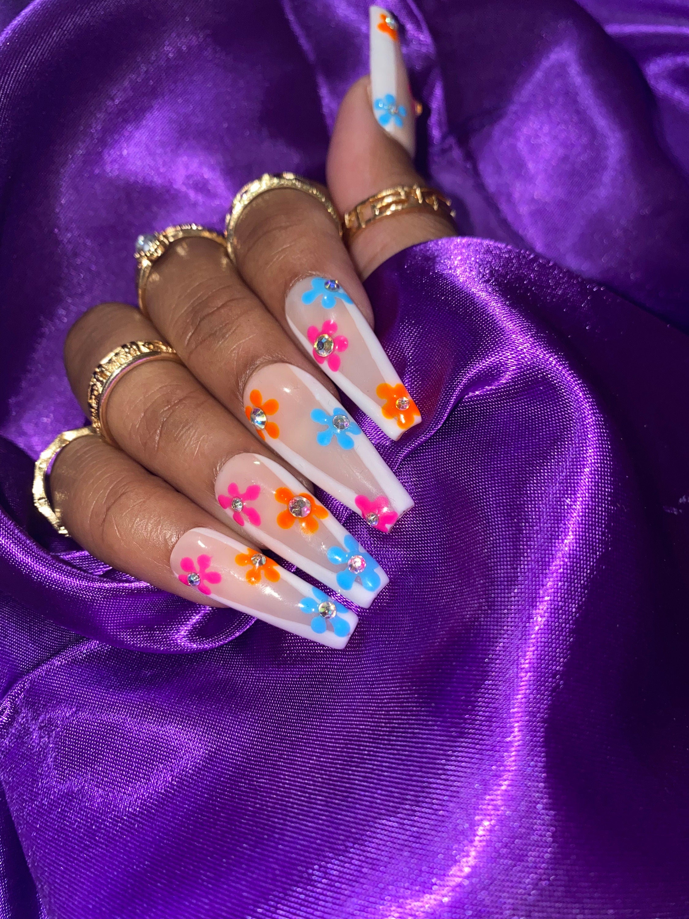 Nails with floral designs on a purple fabric background