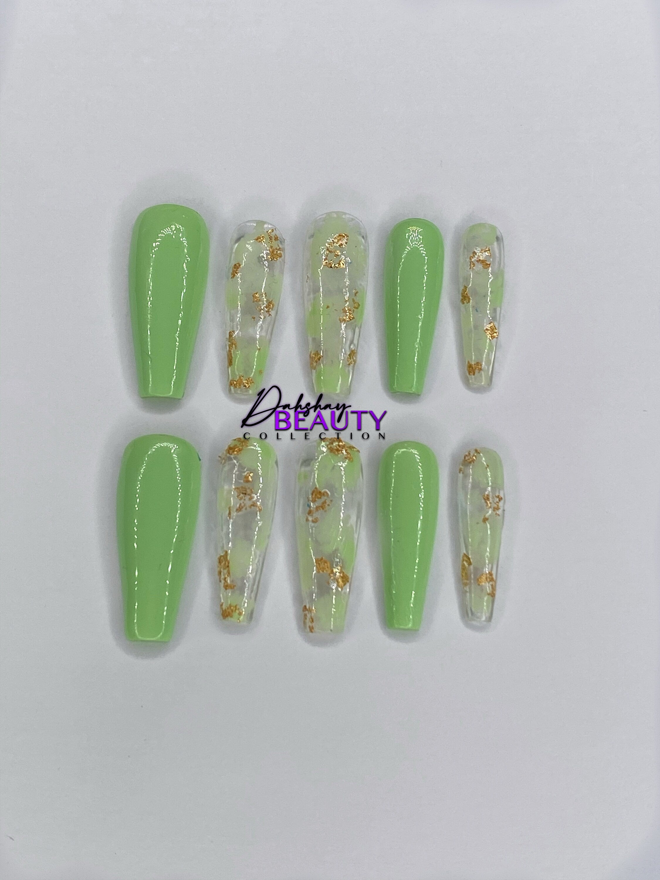 Set of green and clear nail extensions with gold accents on a white background.