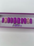 Purple press on nails with a floral design in a display case.