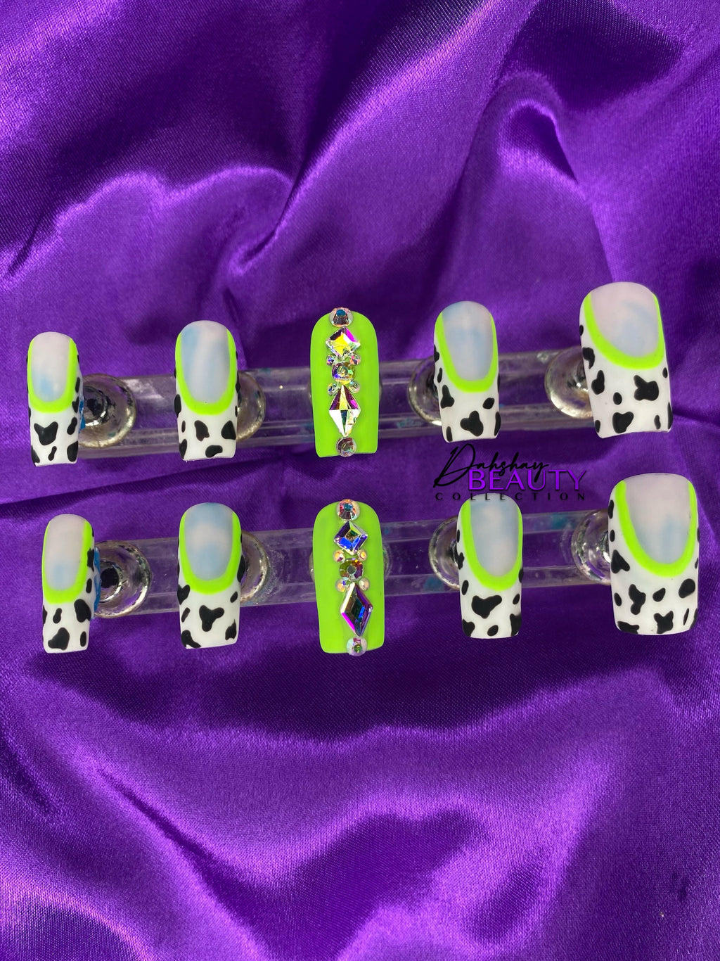 Set of false nails with cow print design on a purple satin background