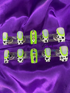 Set of false nails with cow print design on a purple satin background