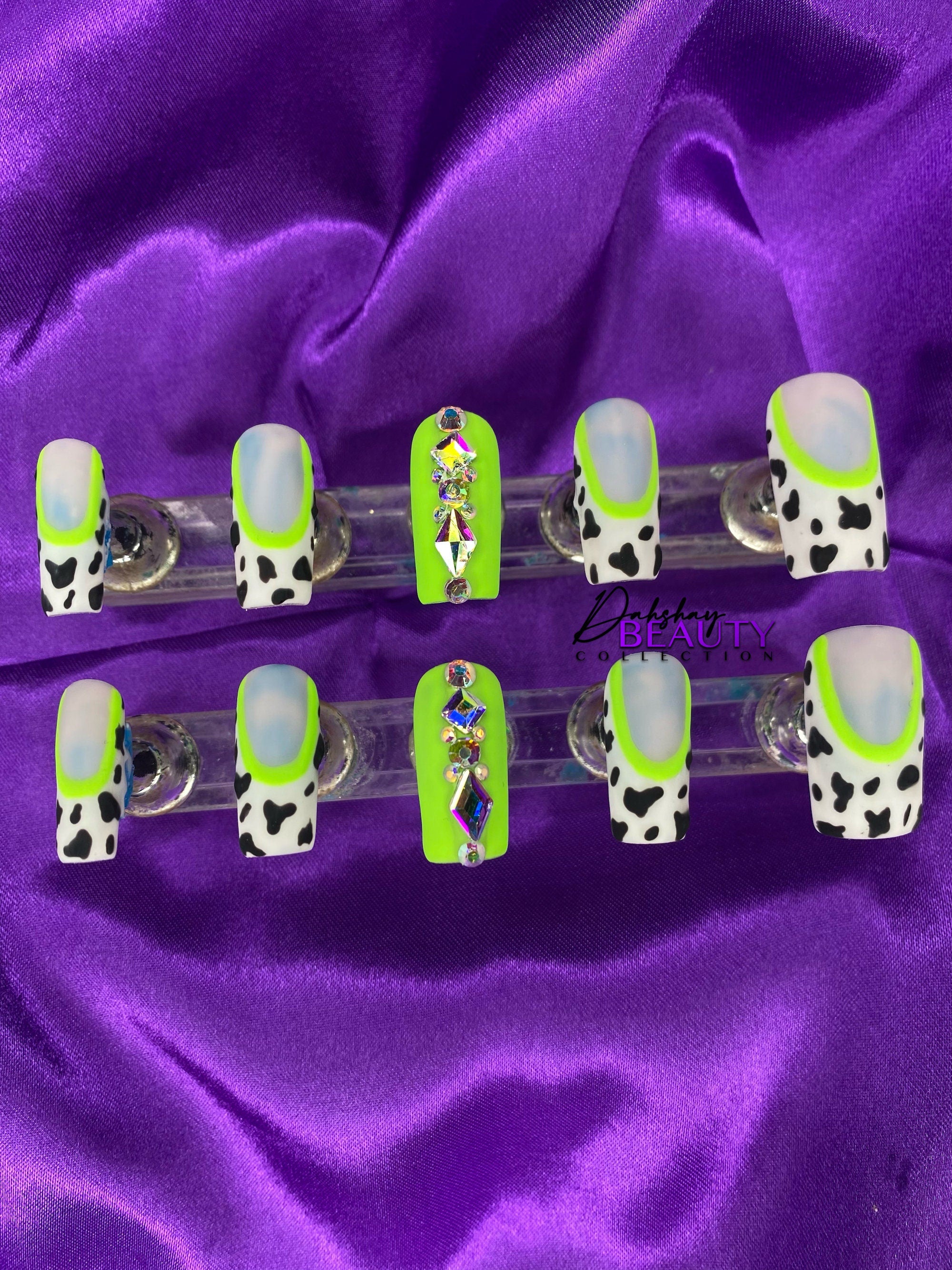 Set of false nails with cow print design on a purple satin background