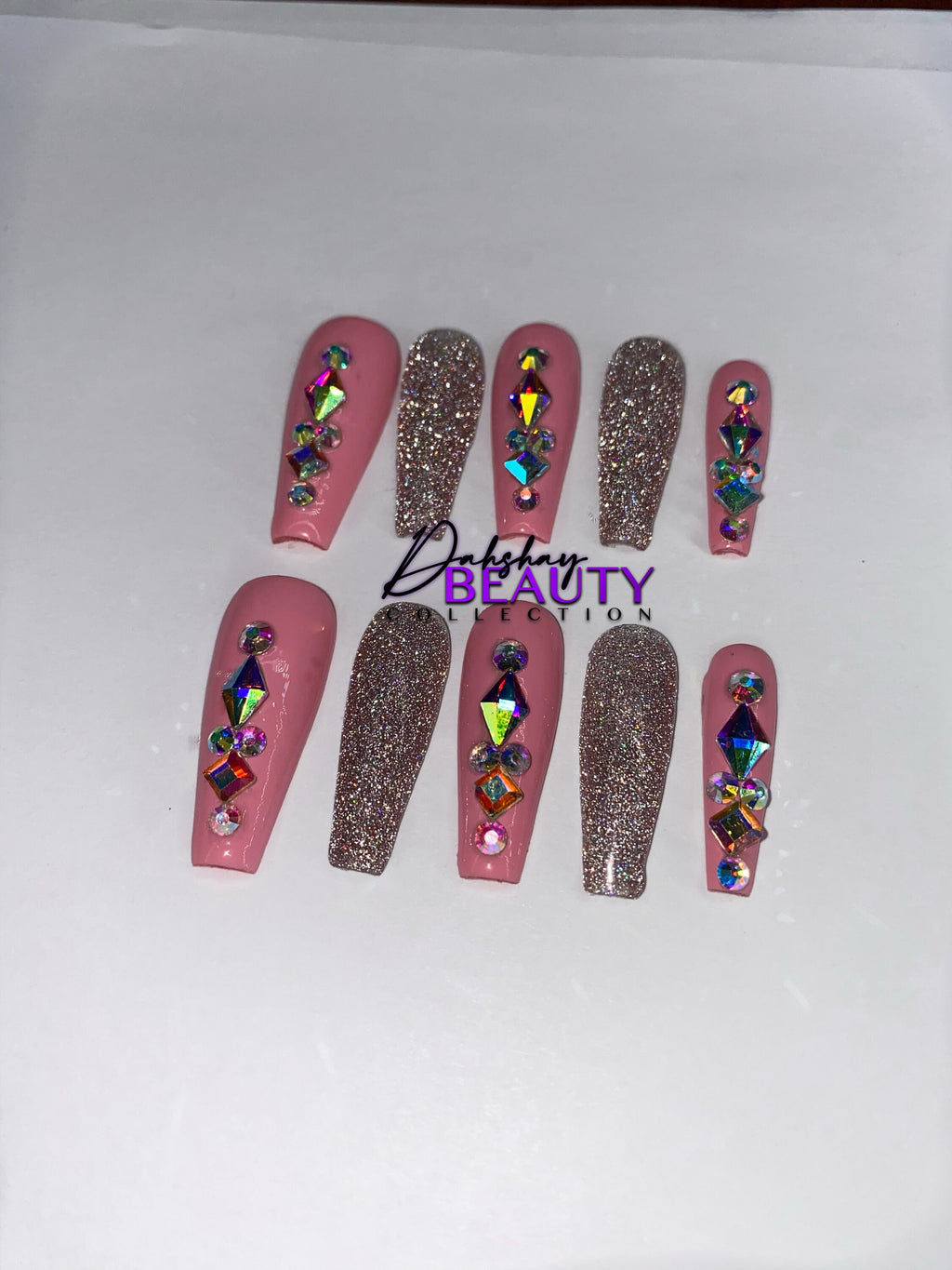 Pink and pink glitter press on nails with rhinestone decorations on a white background.