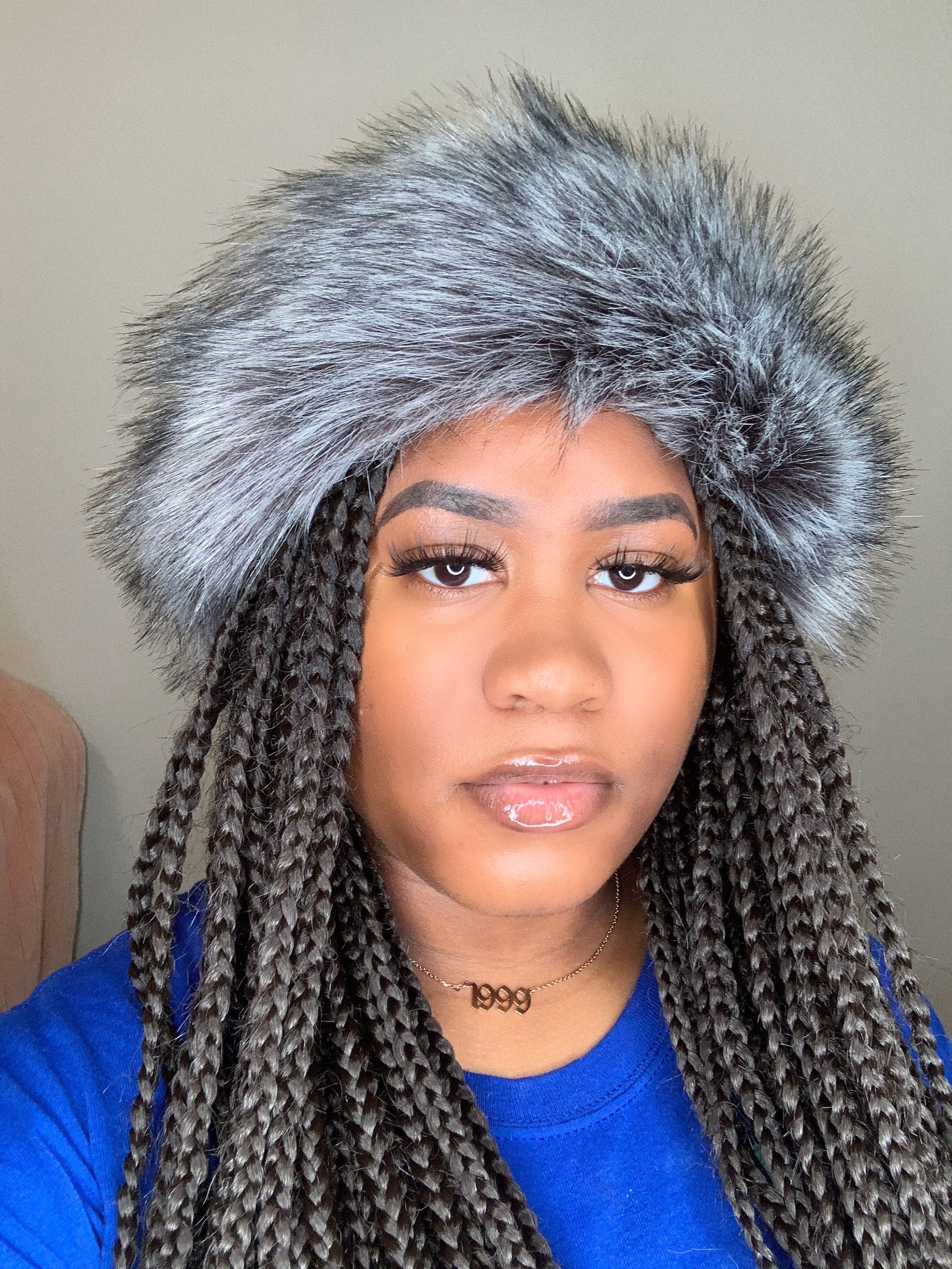 Person wearing a grey furry headband with a neutral background