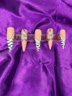 Set of decorative false nails with zebra pattern and a blue flower with black dots on the edge on a purple satin background