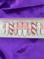 Set of Christmas false nails with snowflake, candy cane and sweater designs on a purple satin background.