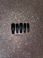 Set of black false nails on a glittery gold background.