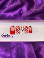 Nail art set with reindeer and candy cane designs on a purple fabric background, featuring the Dahshay Beauty Collection logo.