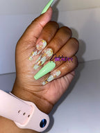 Hand with green  nails with gold accents, wearing a pink smartwatch on a white background.
