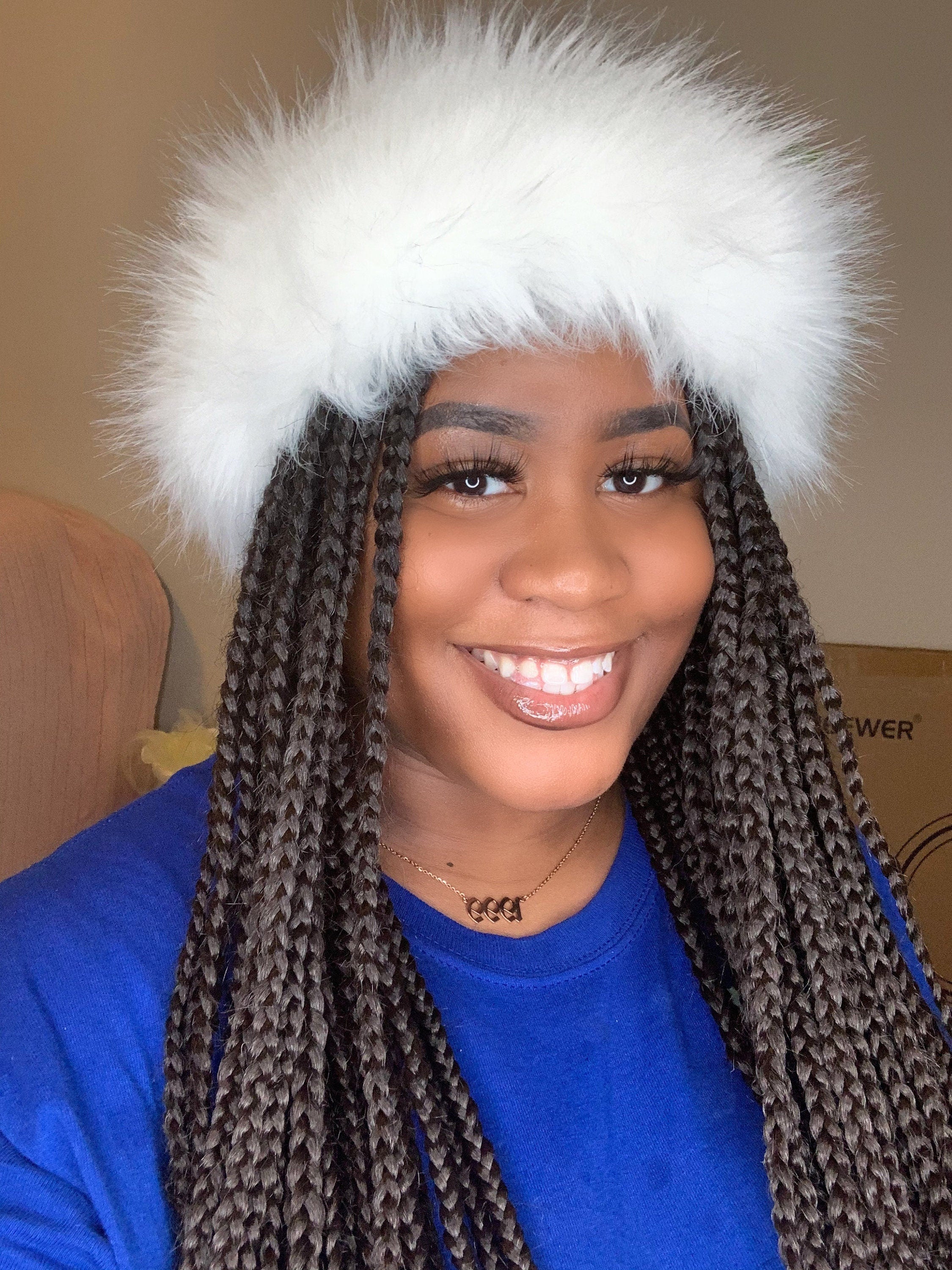 Person wearing a white furry headband with a neutral background