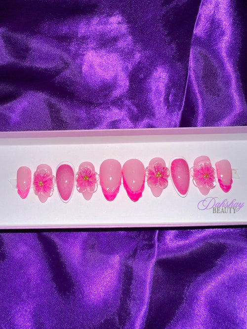 Set of pink floral press on nails on a purple satin background