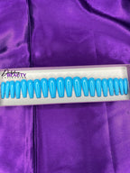 Set of blue false nails in a white and light purple box on a purple fabric background