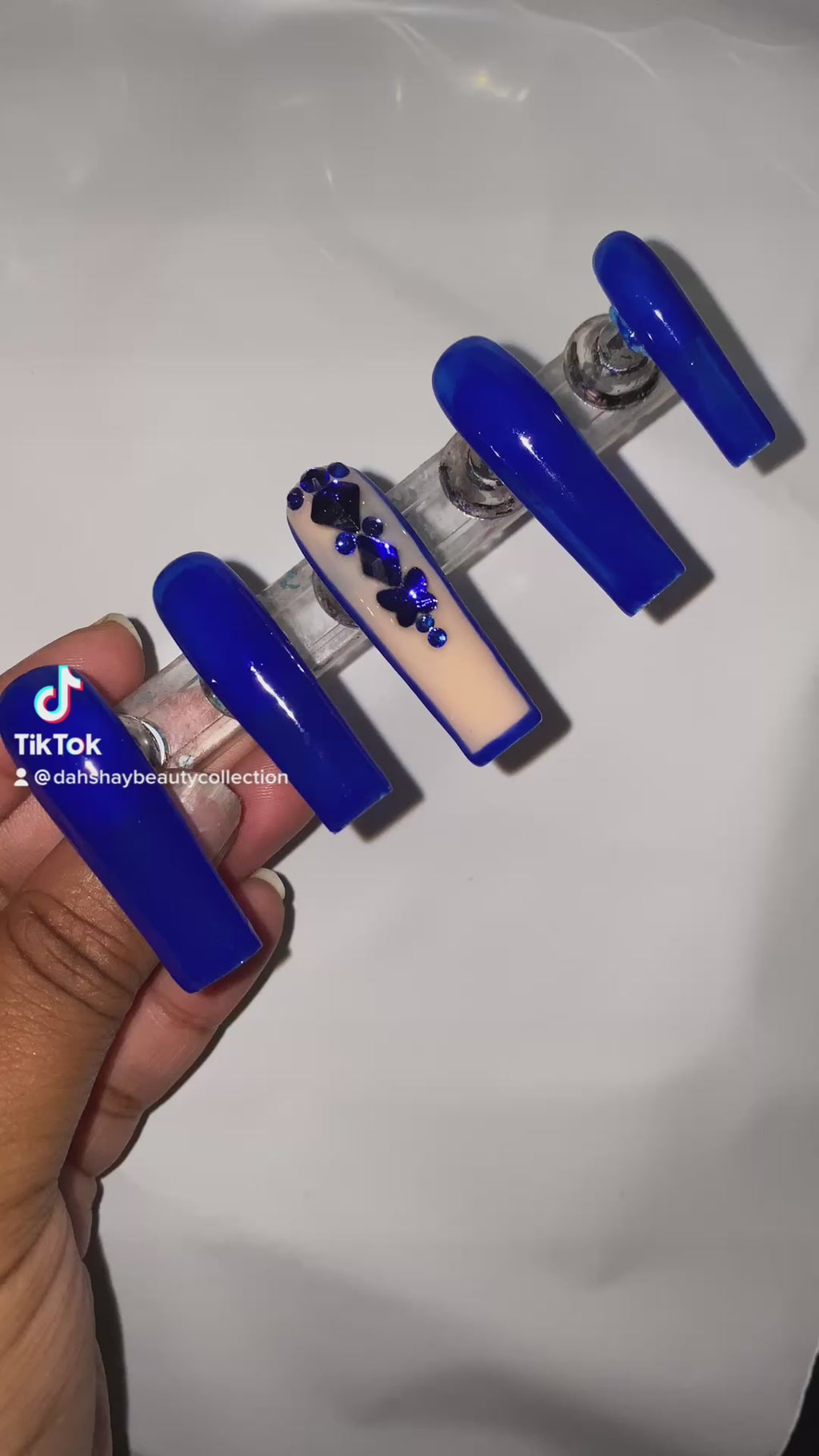 Blue nails with a rhinestone design on a white background