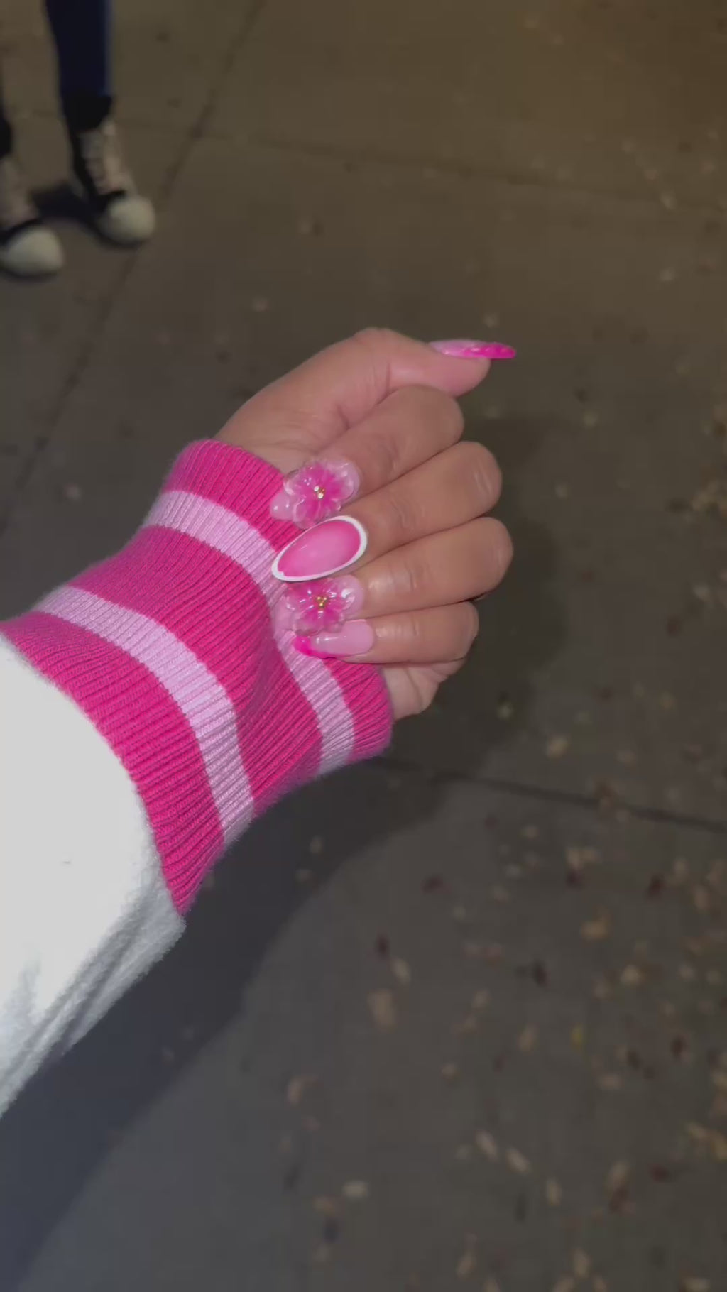 A video of a set of pink floral press on nails on a purple satin background