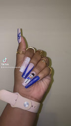 A video of press on nails with Christmas designs of snowmen, bows  and a snowflake on a hand with a plain background.