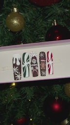 A video of a set of Christmas gingerbread themed nail art designs on a white tray with a decorated Christmas tree in the background.